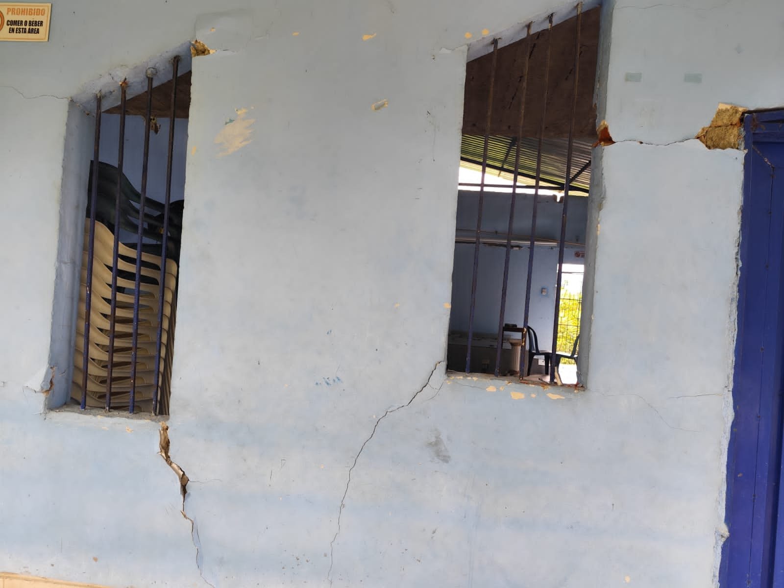 Grietas en la fachada de infraestructura comunitaria, junto a ventanas enrejadas